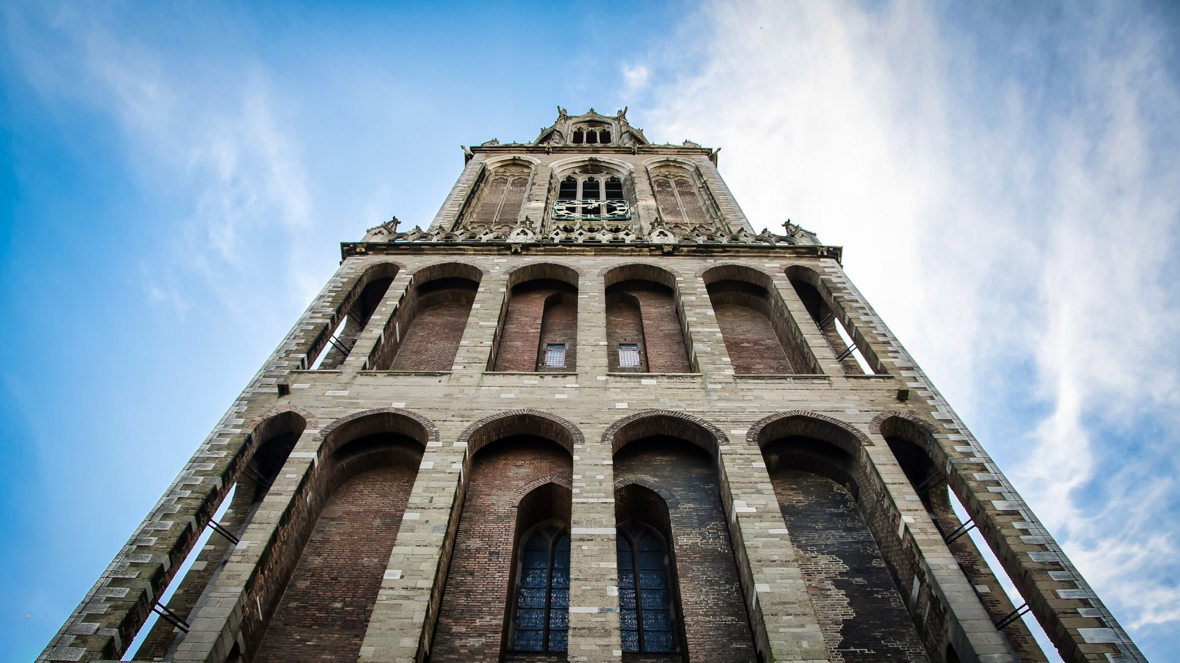 De Utrechtse Domtoren vanaf de grond gezien tegen een blauwe lucht met witte wolken