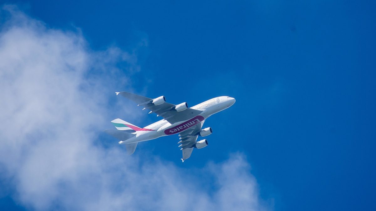 Een Emirates Airbus A380 vliegt door een blauwe lucht met lichte wolken.