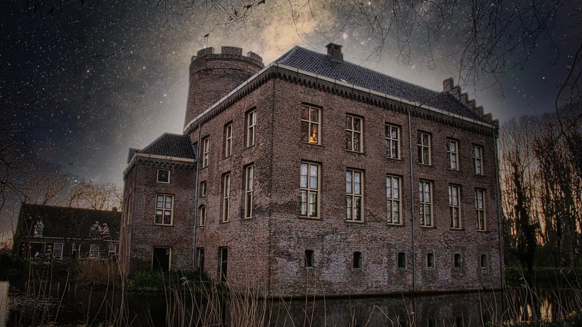 Een verlicht kasteel staat onder een heldere Melkweg in de nacht.