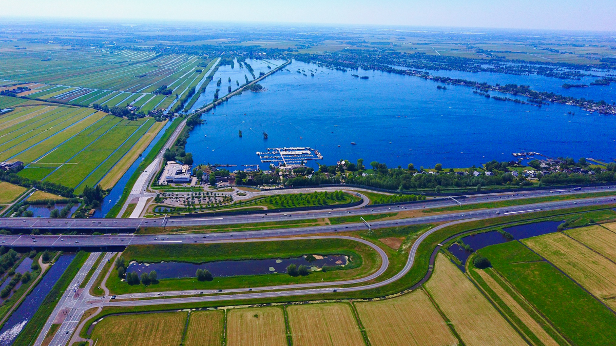 Luchtfoto van een plas, snelweg en polderlandschap