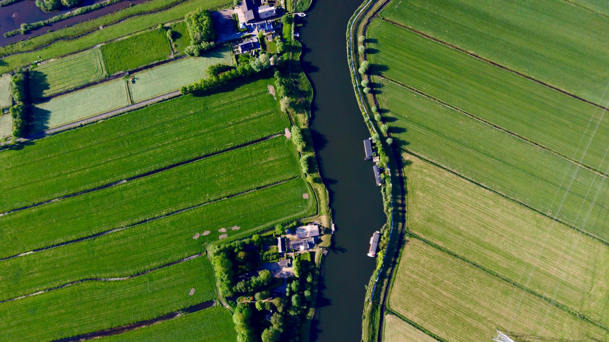 Luchtfoto van groene polderpercelen langs een vaart